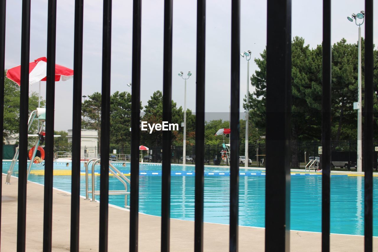 CLOSE-UP OF SWIMMING POOL BY TREES AGAINST SKY