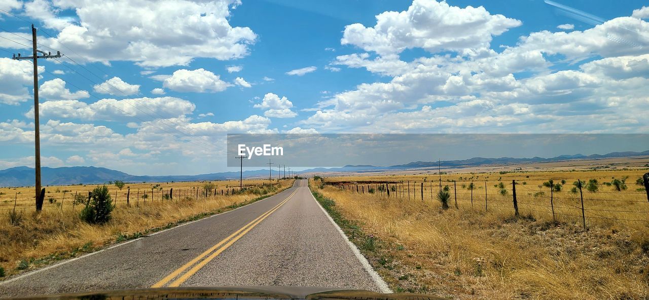 ROAD LEADING TOWARDS FIELD AGAINST SKY
