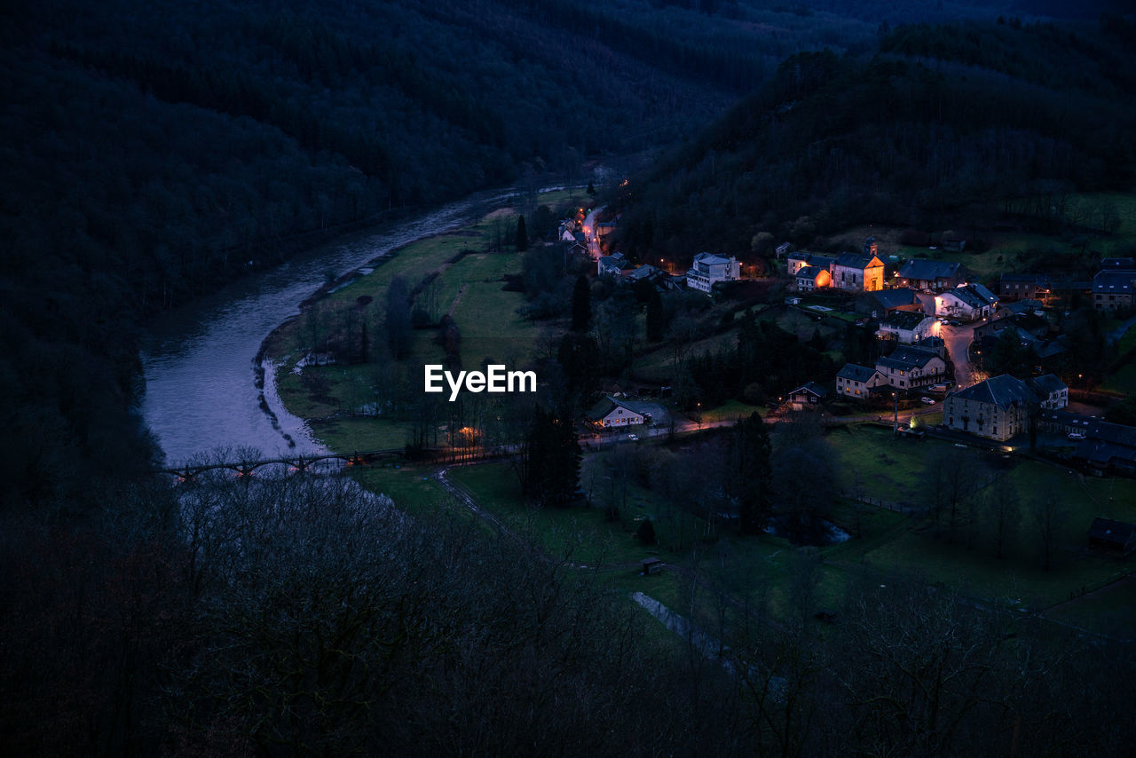 HIGH ANGLE VIEW OF ILLUMINATED BUILDING BY LAKE AT NIGHT