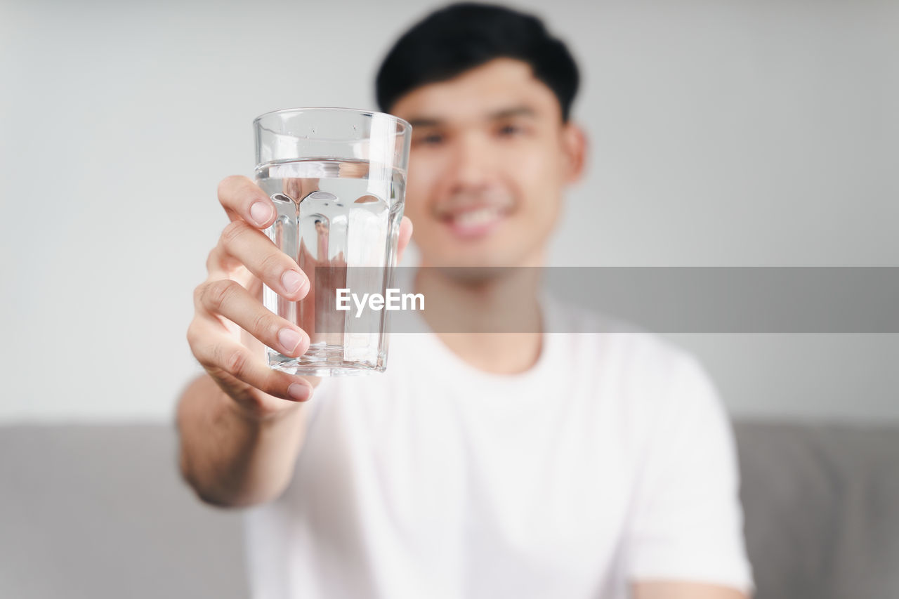 PORTRAIT OF SMILING MAN HOLDING DRINK