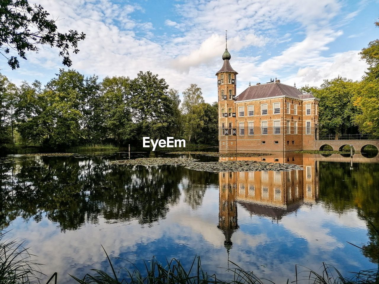 REFLECTION OF BUILDING IN LAKE AGAINST SKY