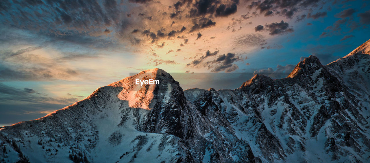 SNOWCAPPED MOUNTAINS AGAINST SKY DURING SUNSET