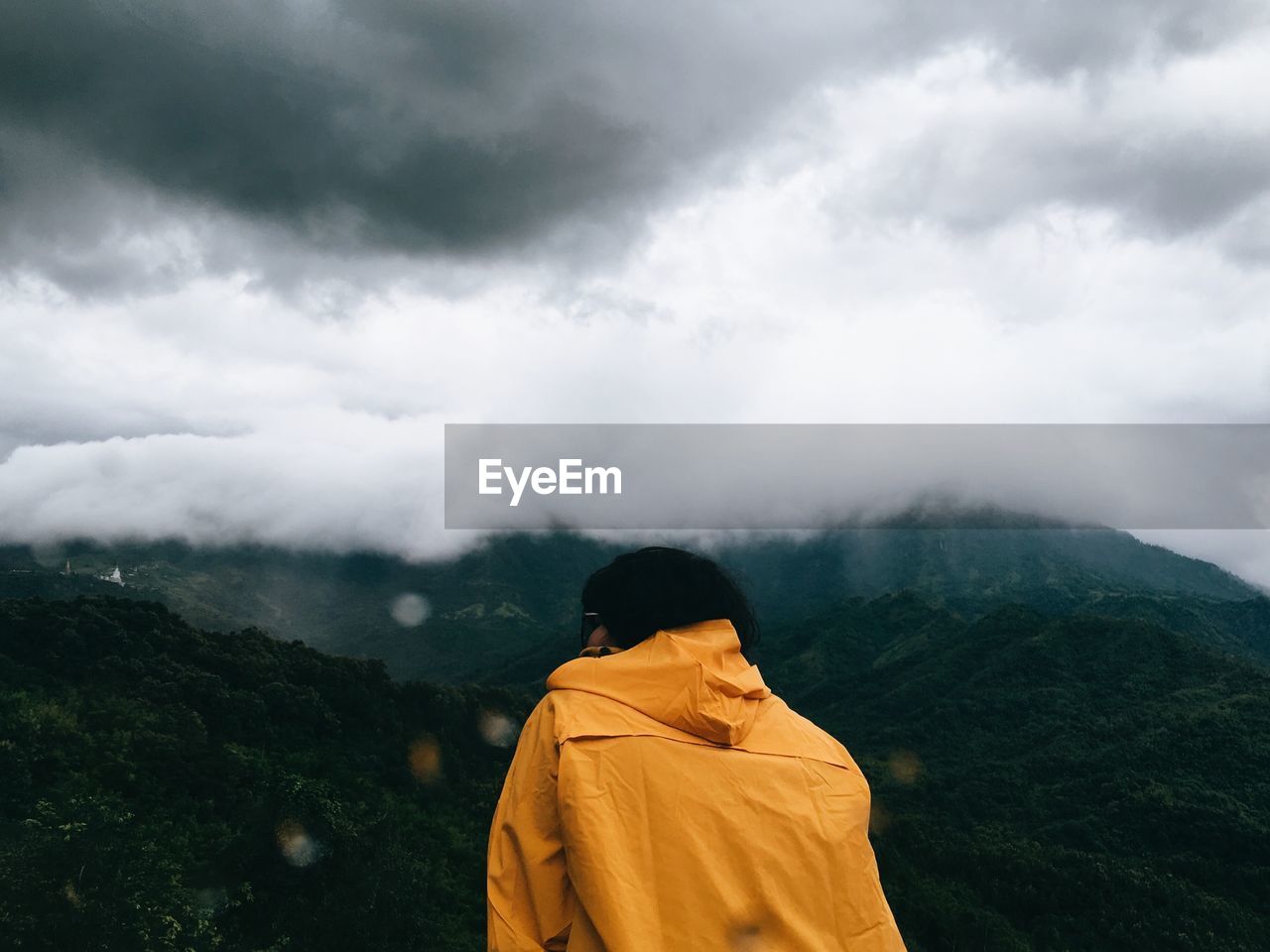 Rear view of person looking at mountains against sky 