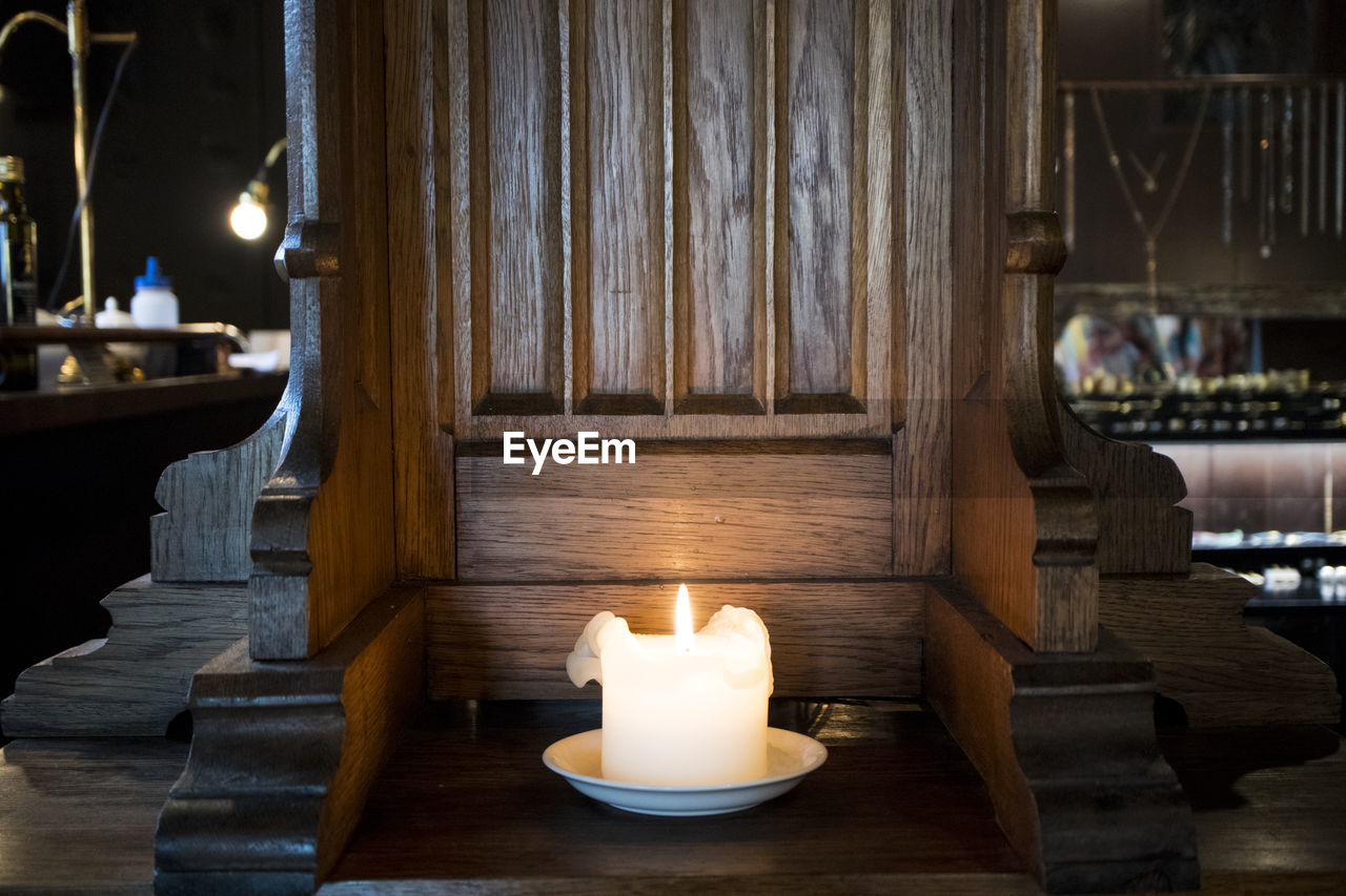 CLOSE-UP OF ILLUMINATED CANDLE ON TABLE