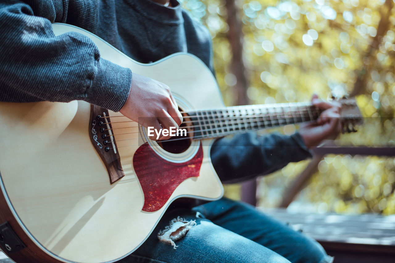 Midsection of man playing guitar