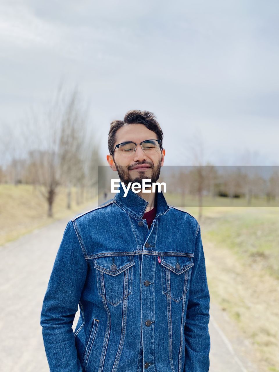 Portrait of young man standing on land with eyes closed