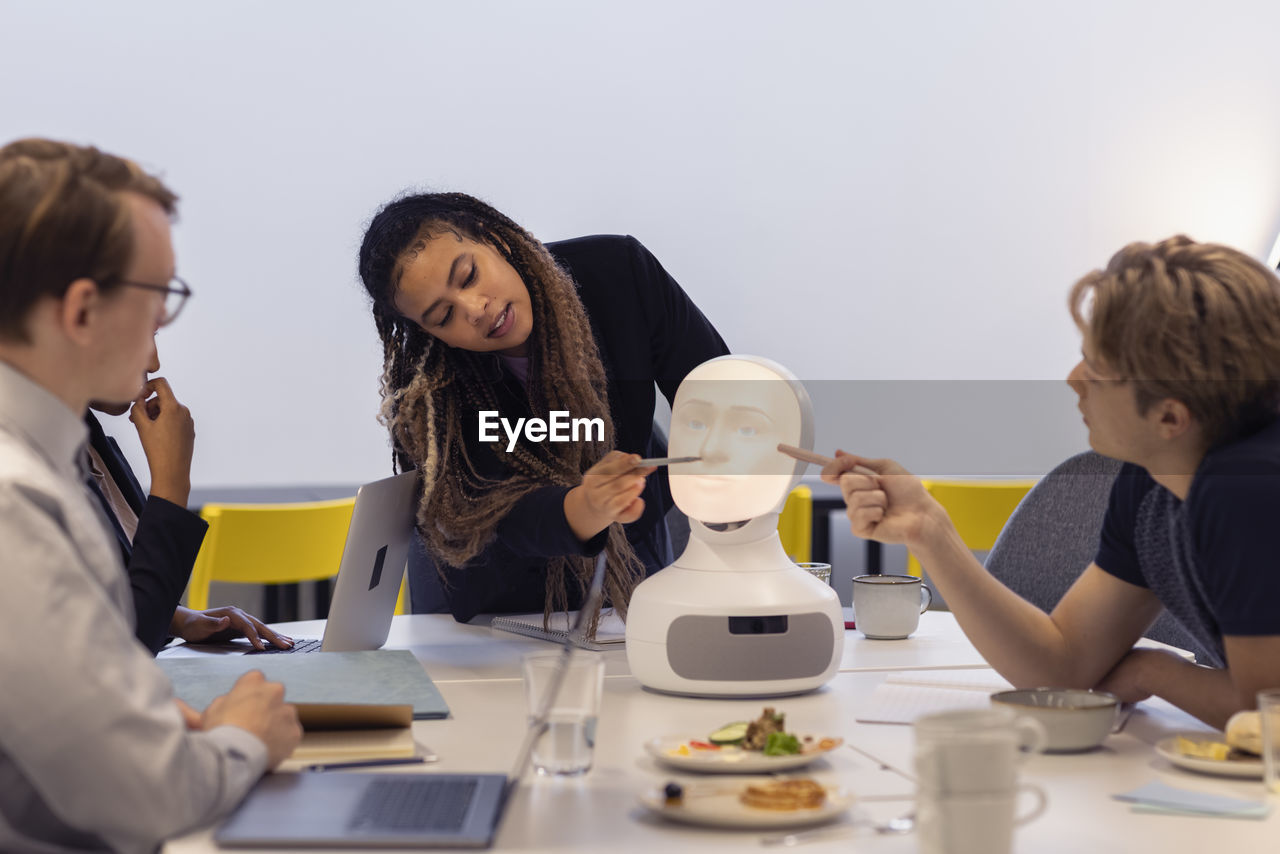 Business people discussing robot voice assistant during meeting