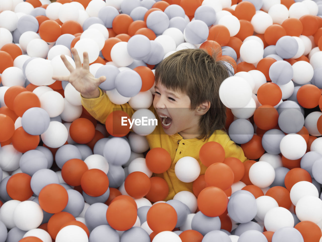 Laughing boy plays in ball pit. plastic balls in dry paddling pool. playroom at kindergarten. 