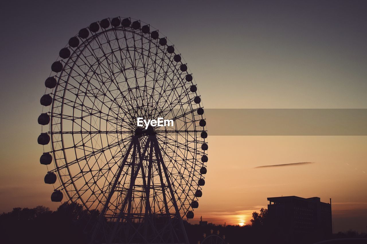 LOW ANGLE VIEW OF FERRIS WHEEL AGAINST SKY AT DUSK