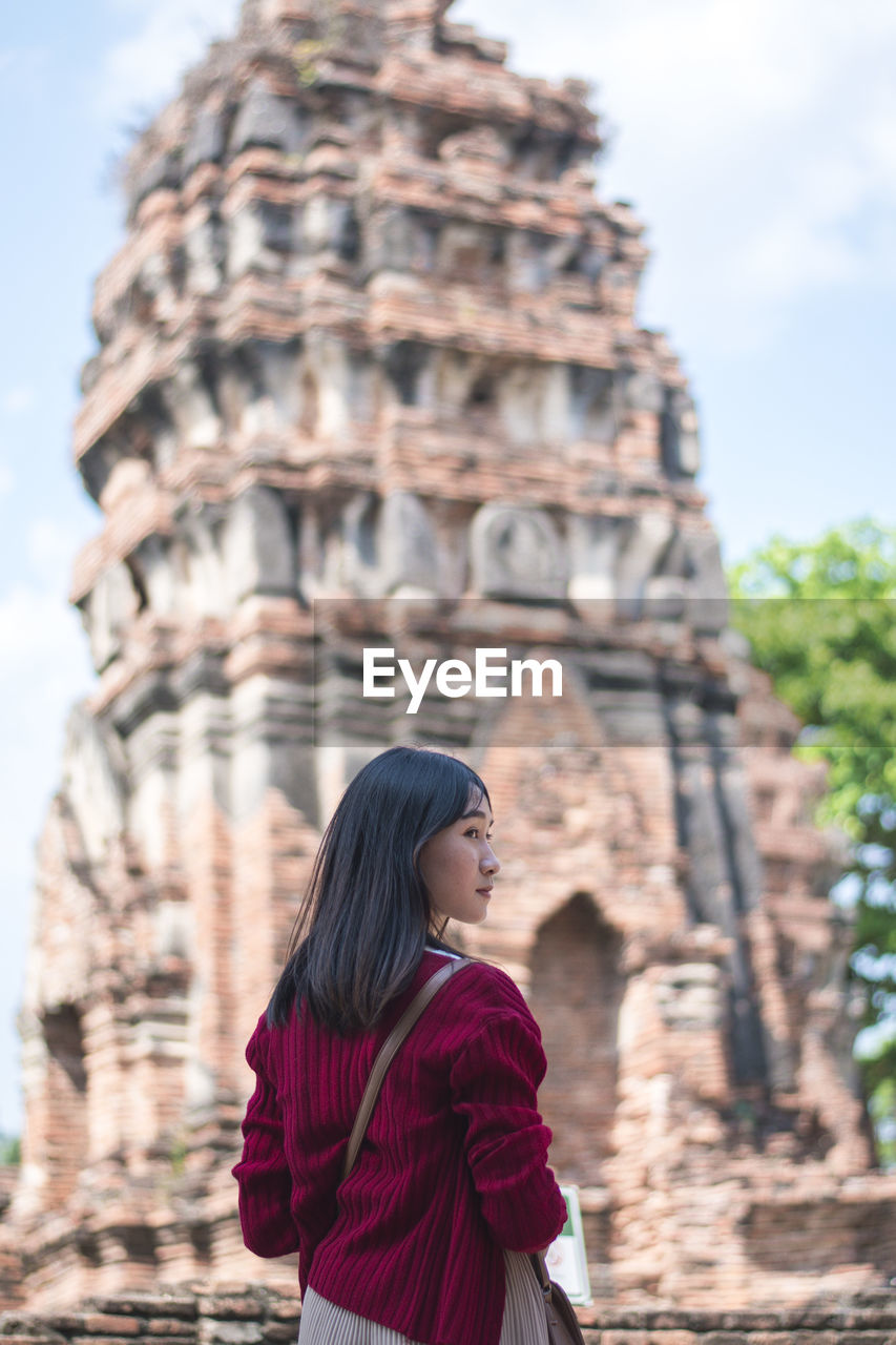 Rear view of young woman standing against historic temple