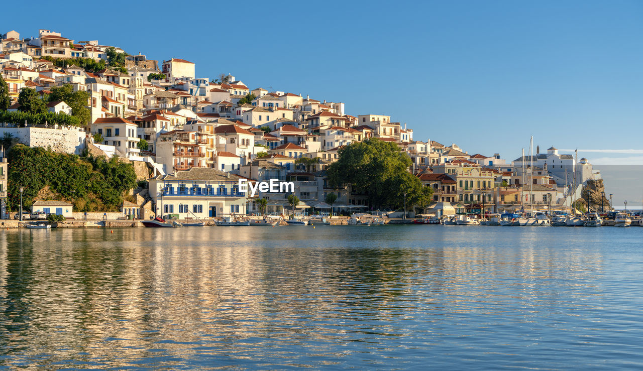 Townscape by sea against clear blue sky