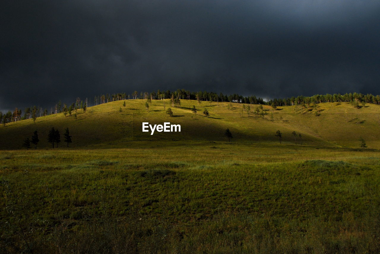 Scenic view of grassy field against cloudy sky