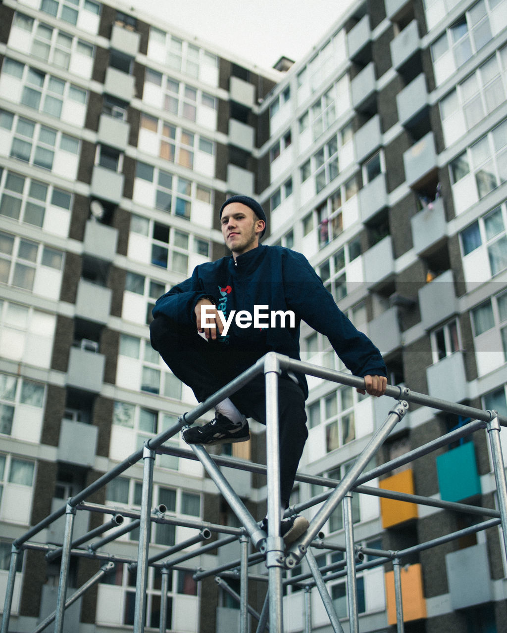 LOW ANGLE VIEW OF A YOUNG MAN AGAINST BUILDING