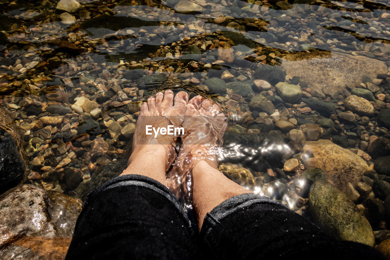 Low section of woman sitting in river