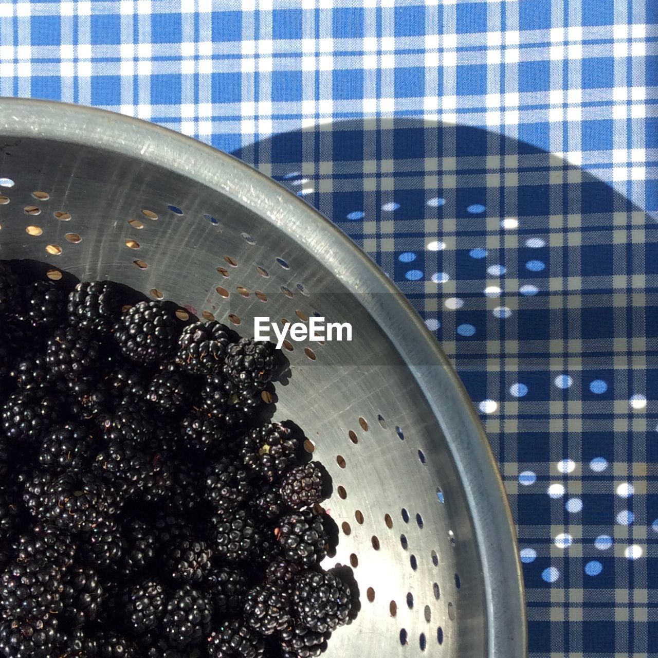 High angle view of blackberries in colander on table