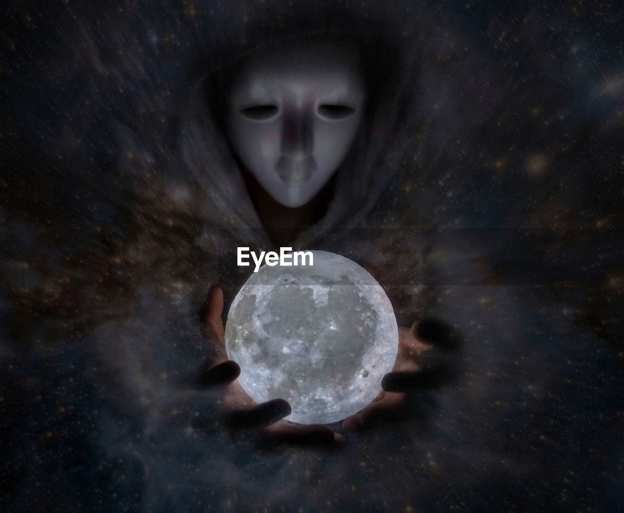 Optical illusion of man wearing mask while holding moon at night