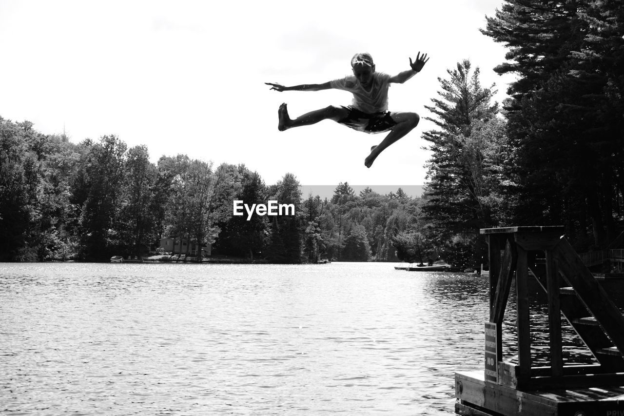 Low angle view of boy jumping in river against clear sky