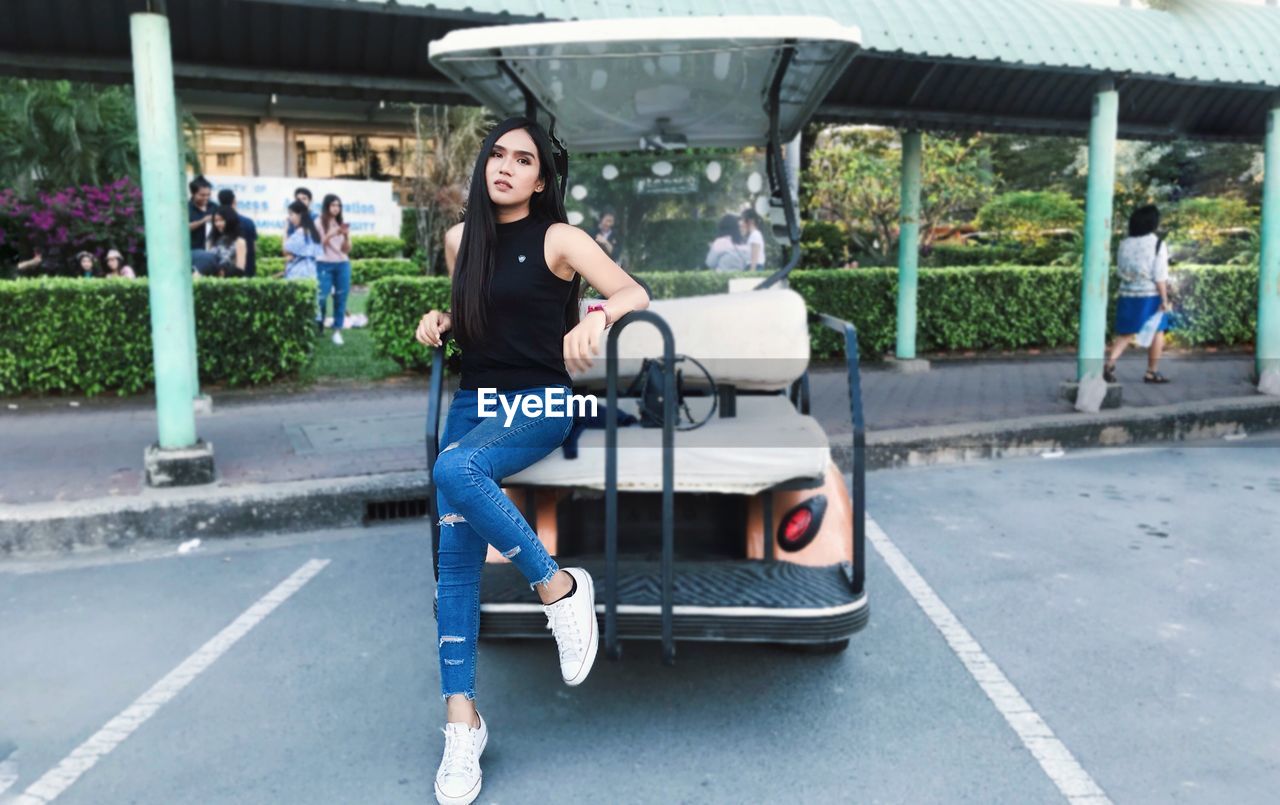 Portrait of young woman sitting on golf cart in city