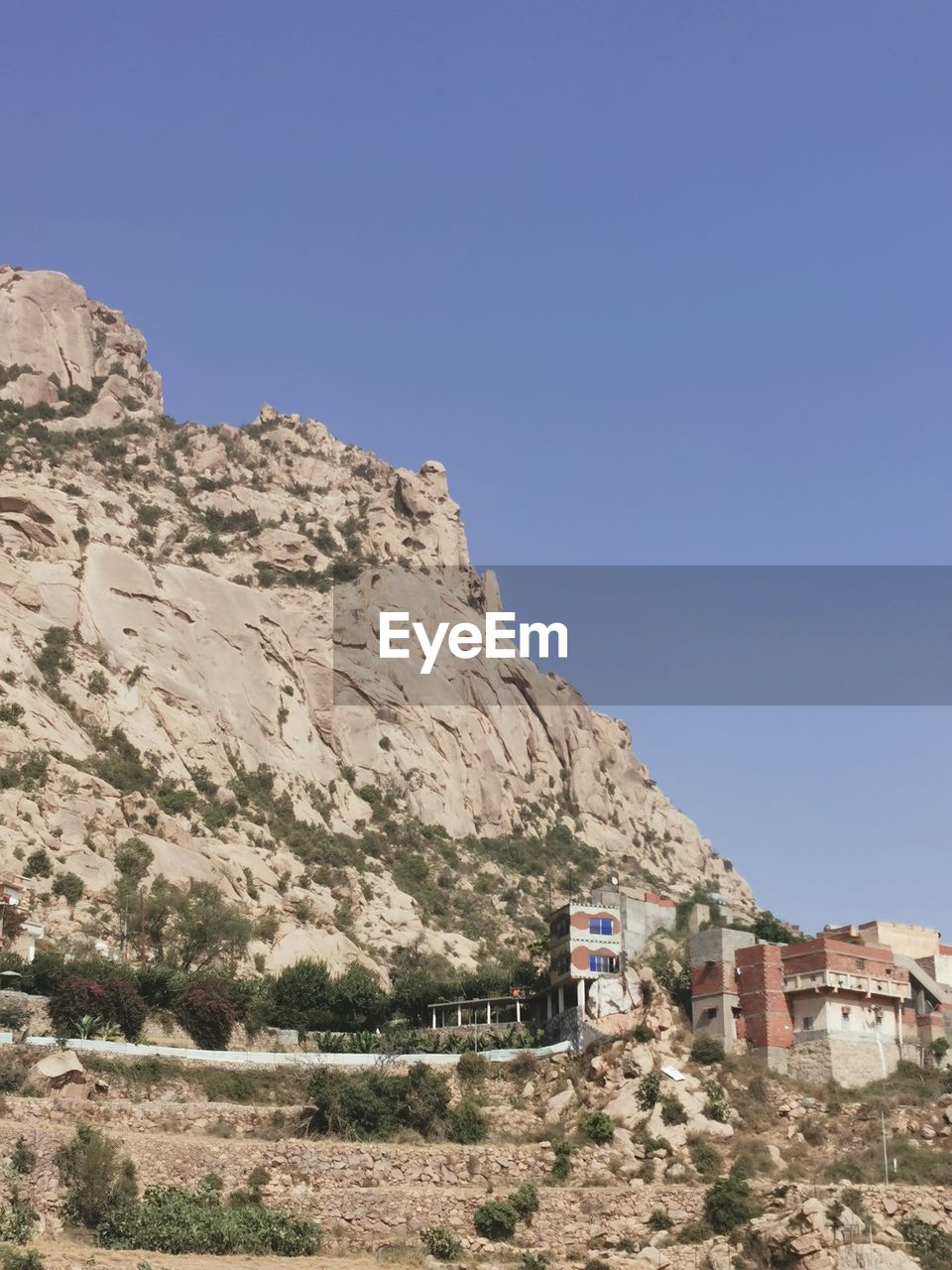 sky, nature, architecture, mountain, wadi, valley, clear sky, landscape, scenics - nature, built structure, land, rock, building, environment, building exterior, blue, no people, travel destinations, travel, day, house, desert, beauty in nature, outdoors, mountain range, geology, sunny, plateau, non-urban scene, plant, copy space, terrain, rock formation, arid climate, tranquility, tourism, climate