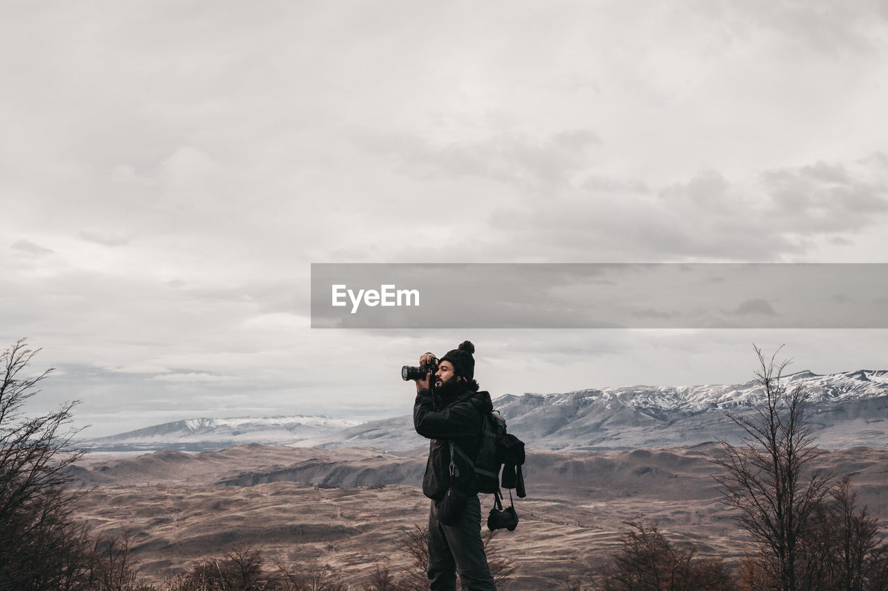 Man photographing on mountain against sky