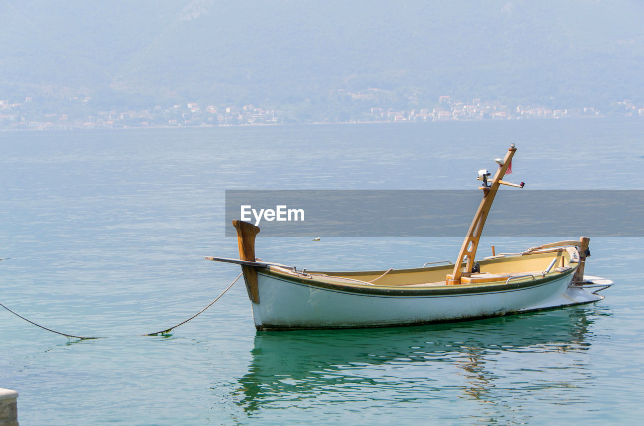 BOAT MOORED IN SEA AGAINST SKY