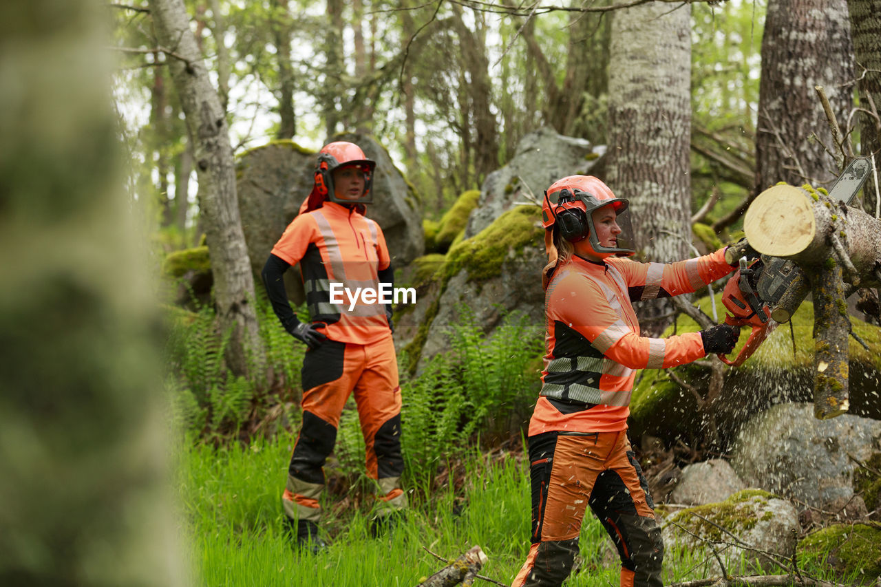 Female lumberjacks cutting log in forest