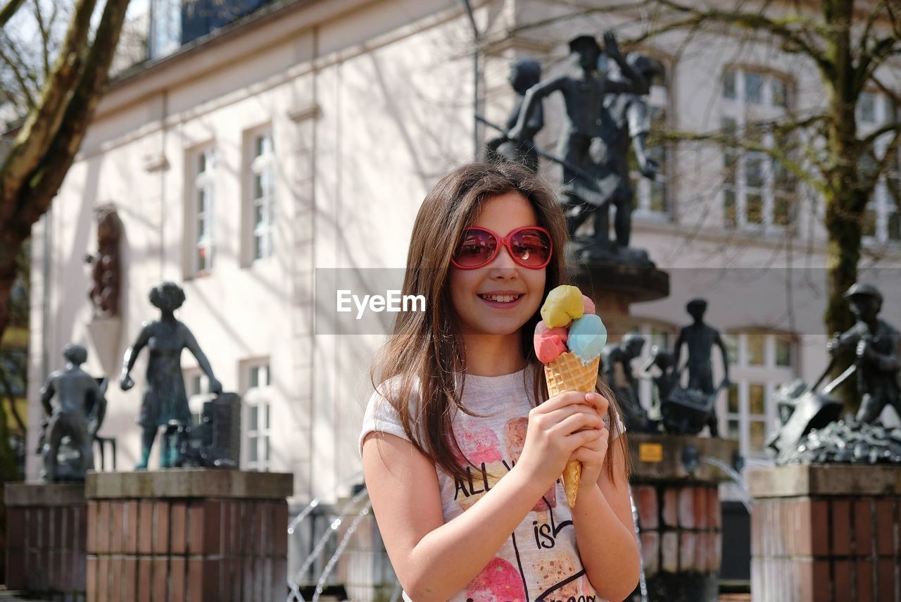 Portrait of happy girl having ice cream cone in city