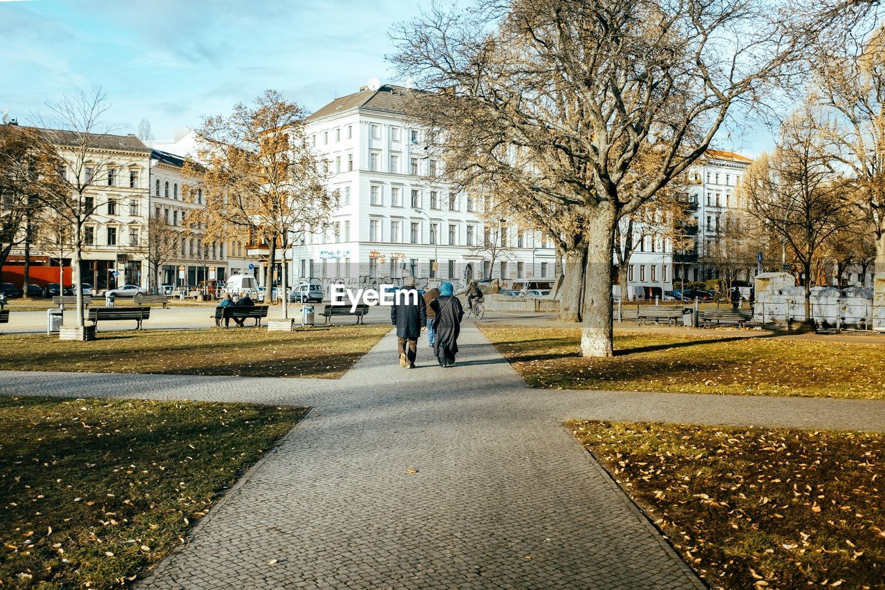 Rear view of people walking on footpath in city