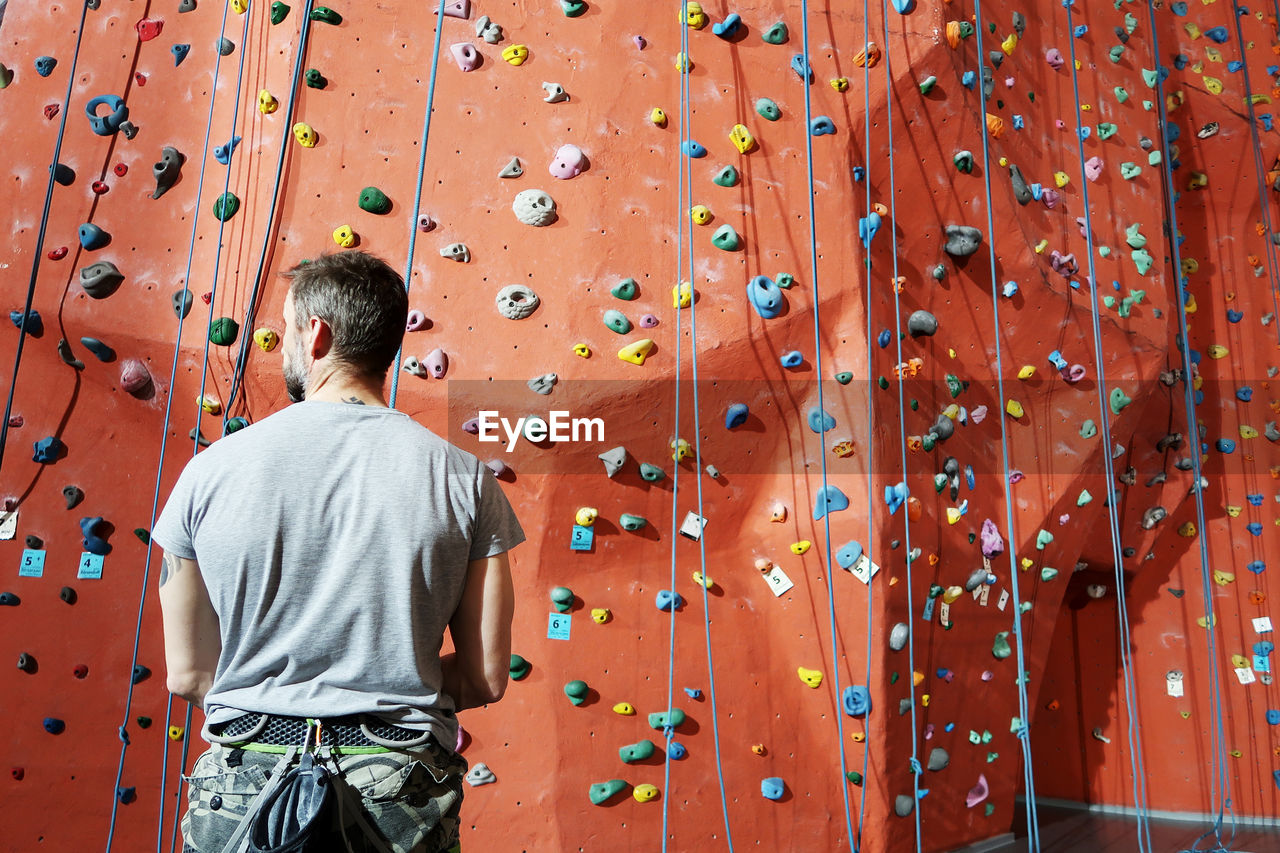 Rear view of man standing against climbing wall