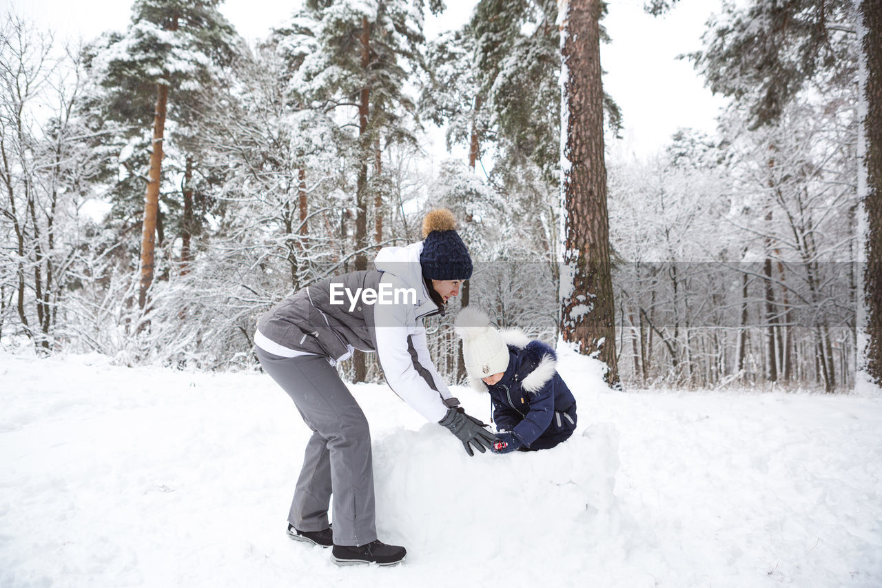 Mom and daughter play snow games, build a fortress, make snowballs. winter entertainment outside,