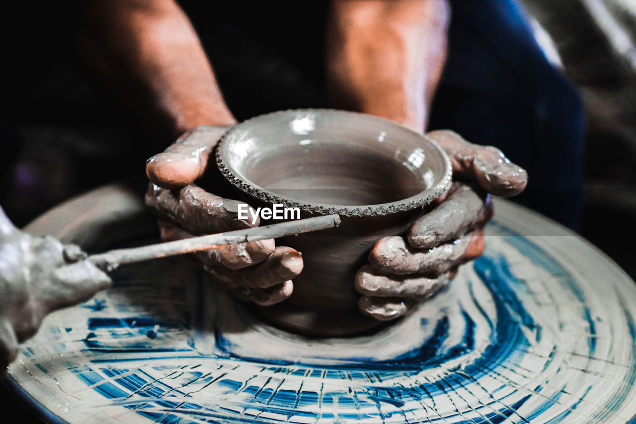 Cropped hands making pot on pottery wheel