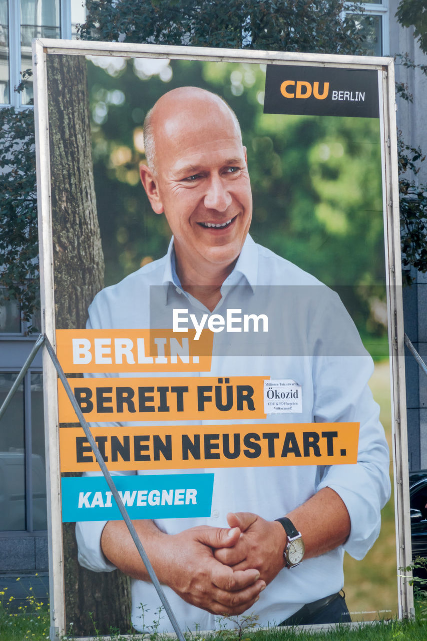 PORTRAIT OF A MAN STANDING ON A SIGN