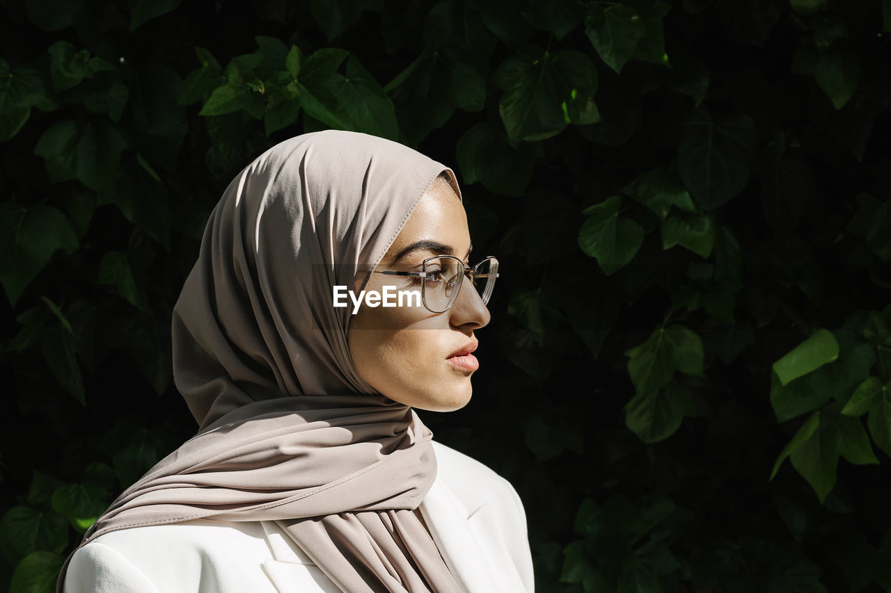 Young woman wearing eyeglasses looking away during sunny day