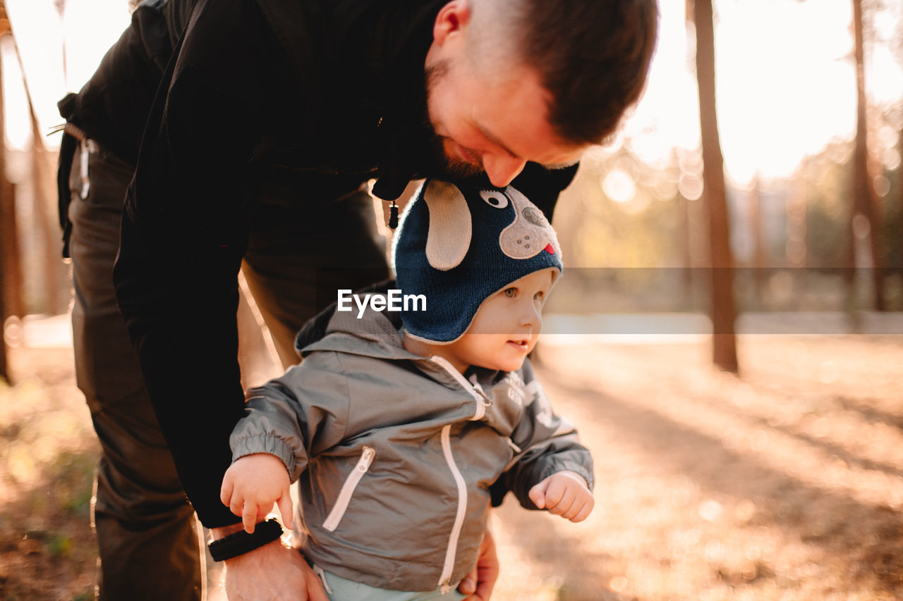 Happy father playing with son outdoors in park during sunny day