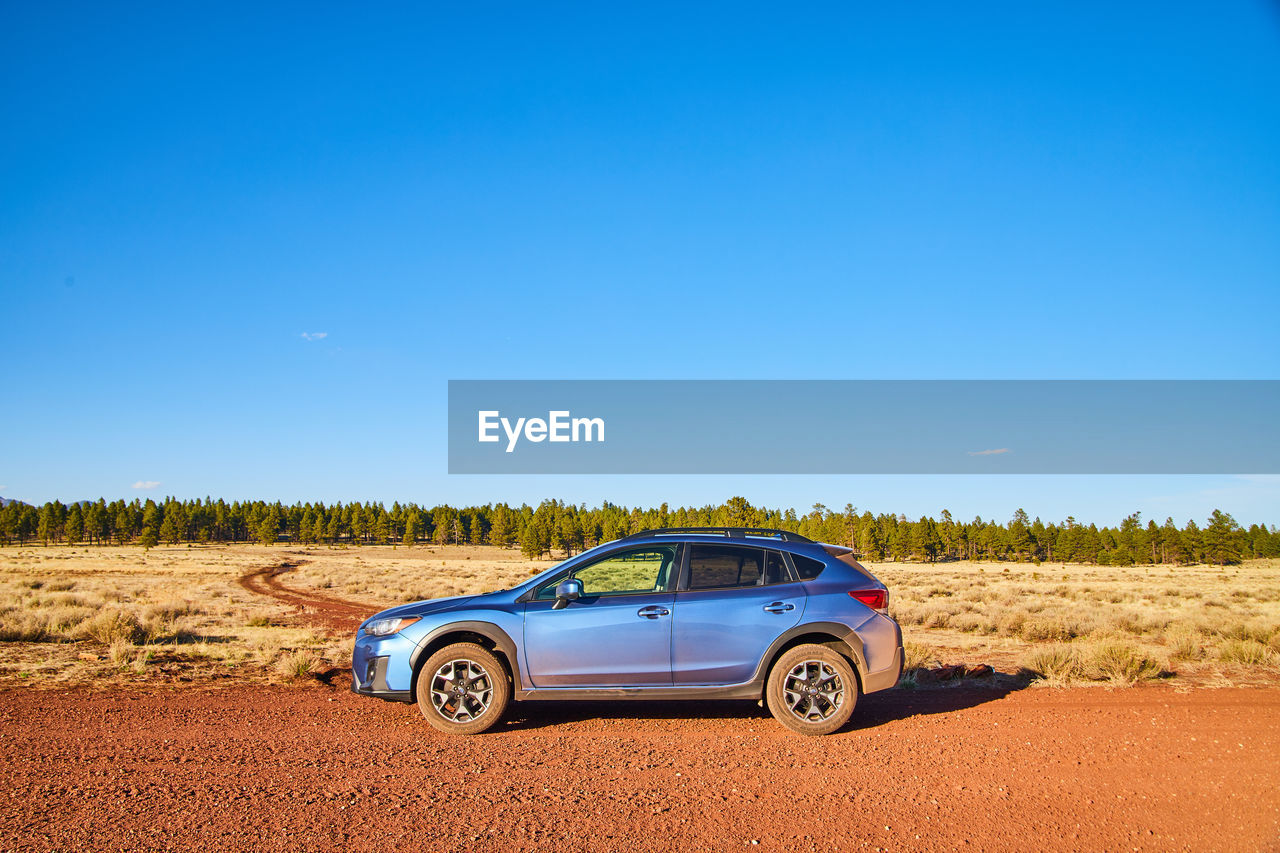 cars on field against clear blue sky