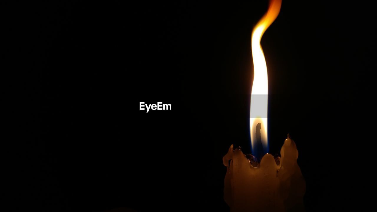 Close-up of lit candle against black background