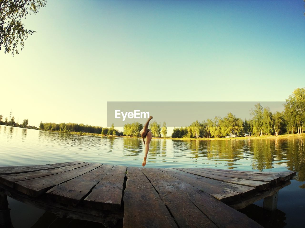 Woman diving in lake against clear blue sky