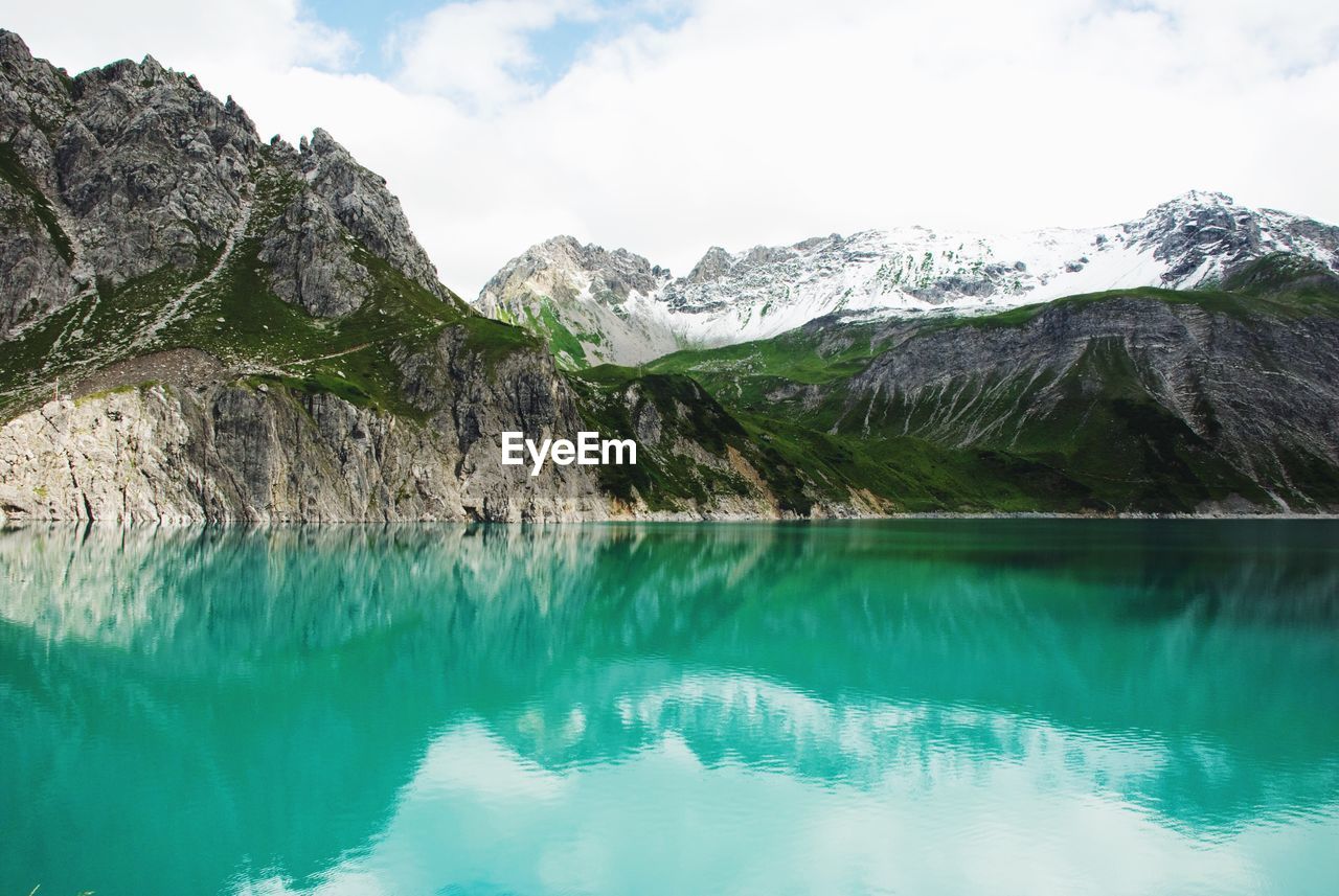 Scenic view of lake by mountains against sky