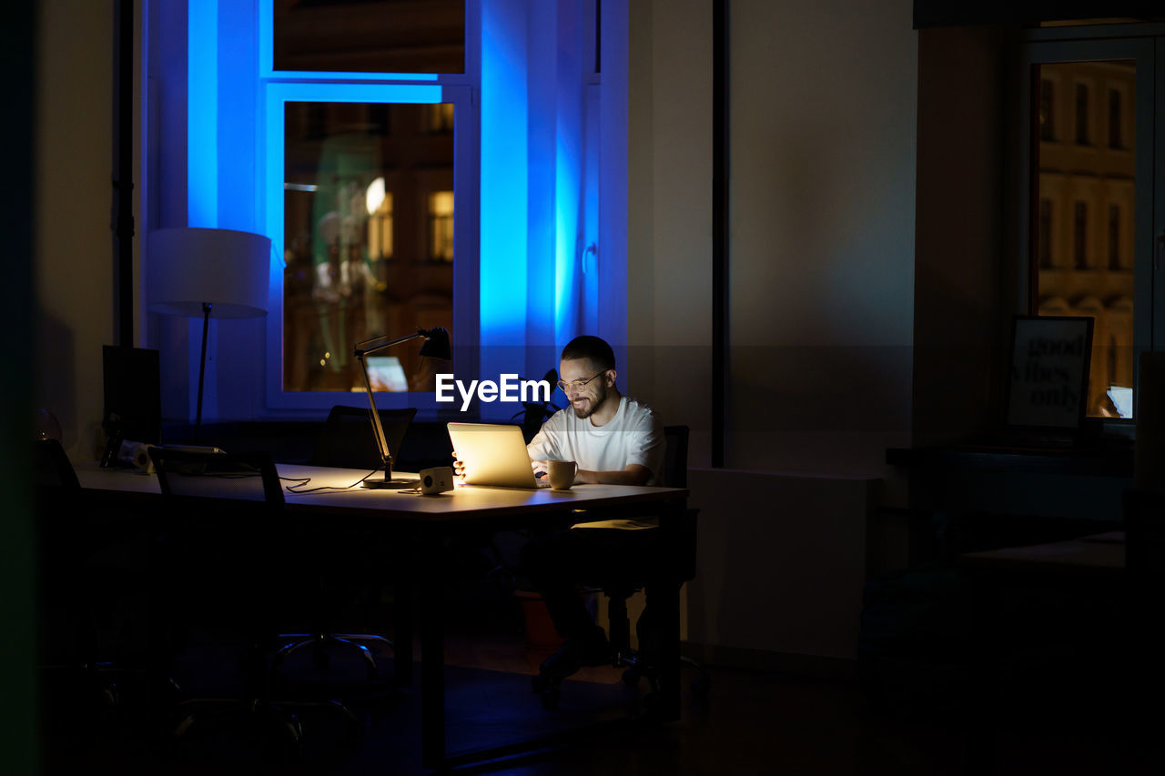 Excited businessman make online video call to colleague or partner in empty dark office overtime