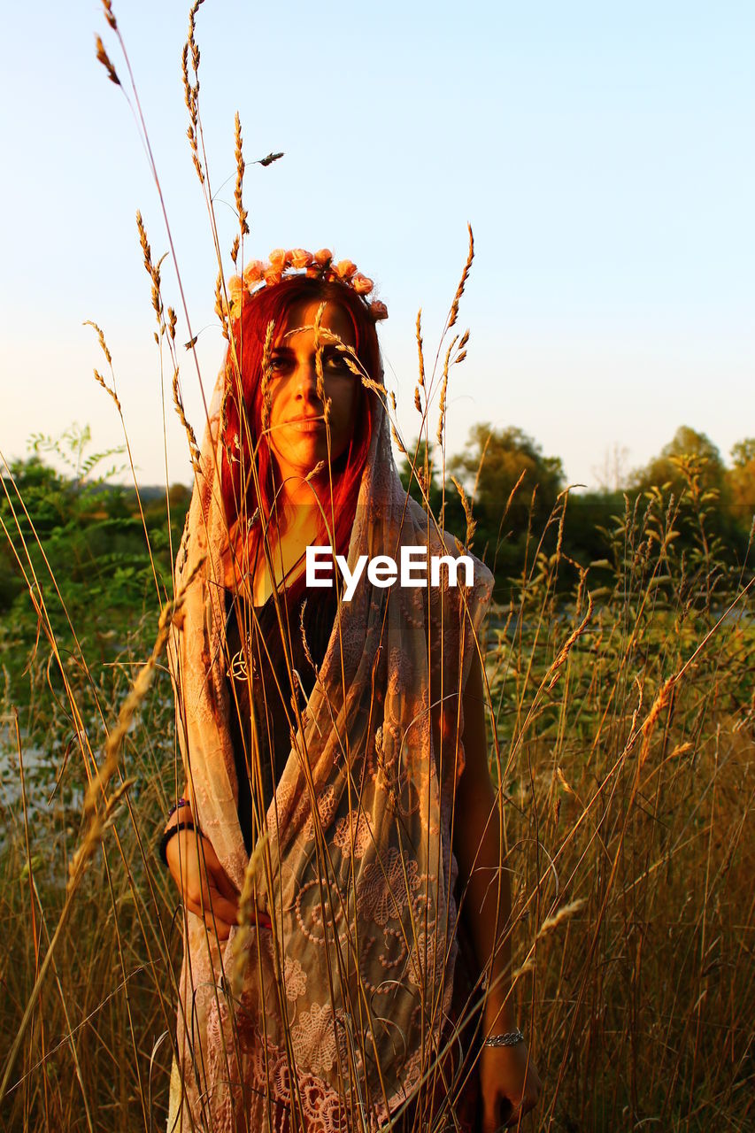 Mid adult woman standing on field against clear sky during sunset