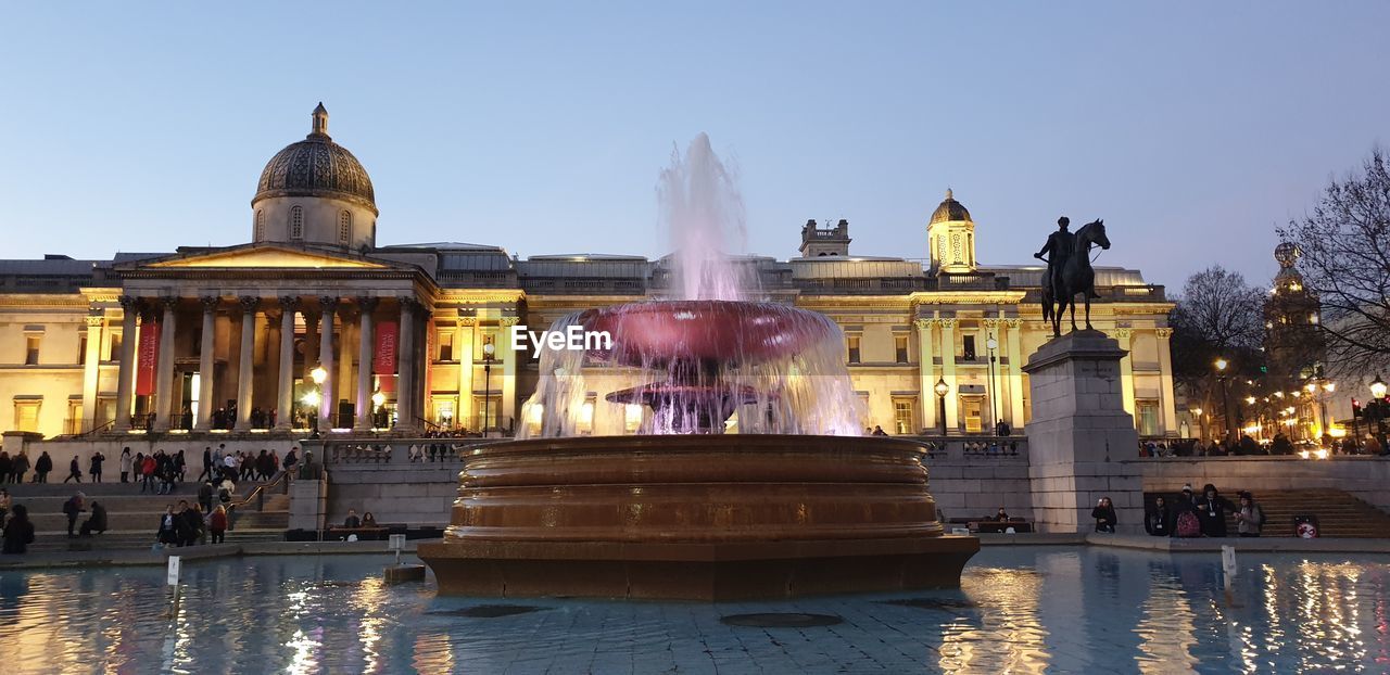 Fountain in front of building against clear sky