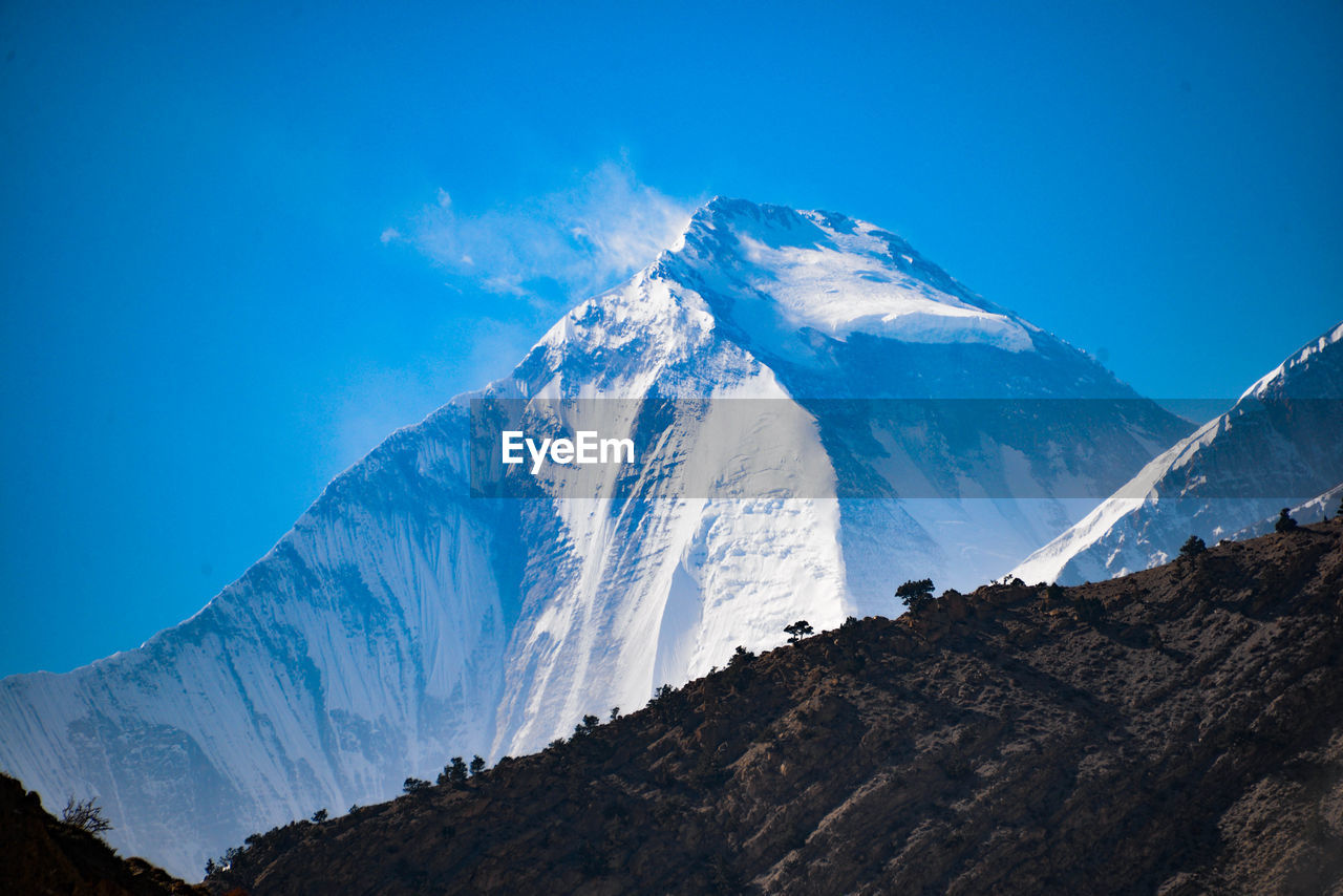 Scenic view of snowcapped mountains against blue sky