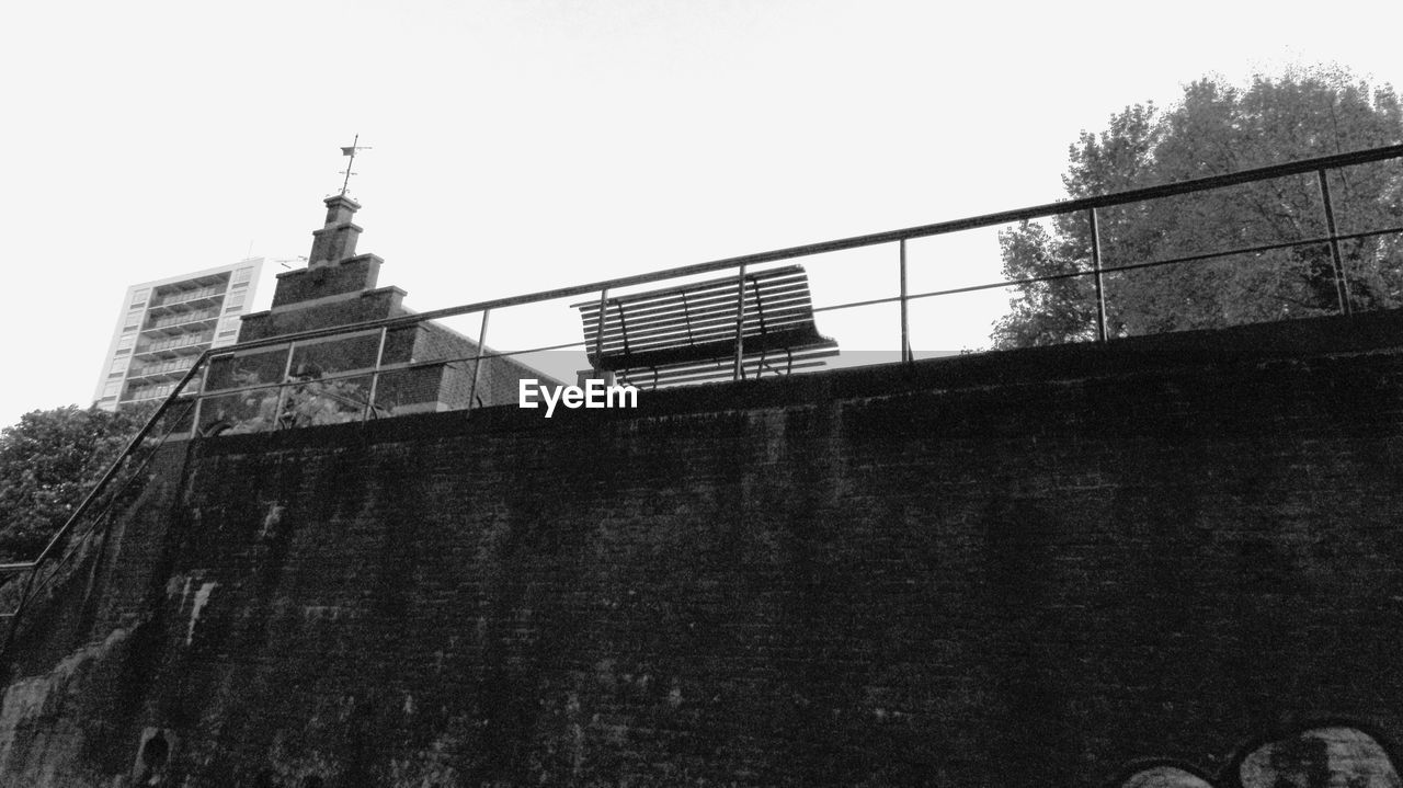 Low angle view of quay wall with bench against sky