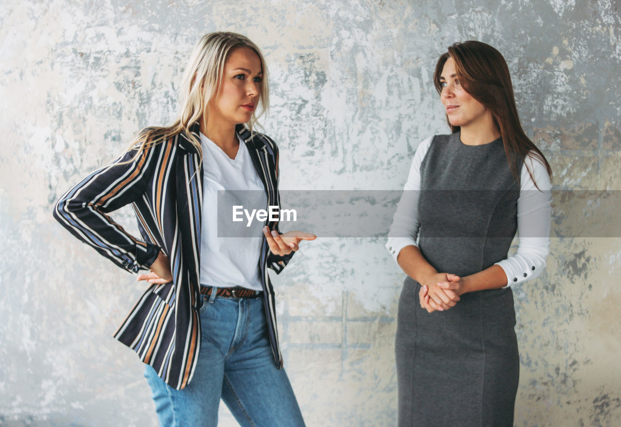 Woman discussing with colleague against wall