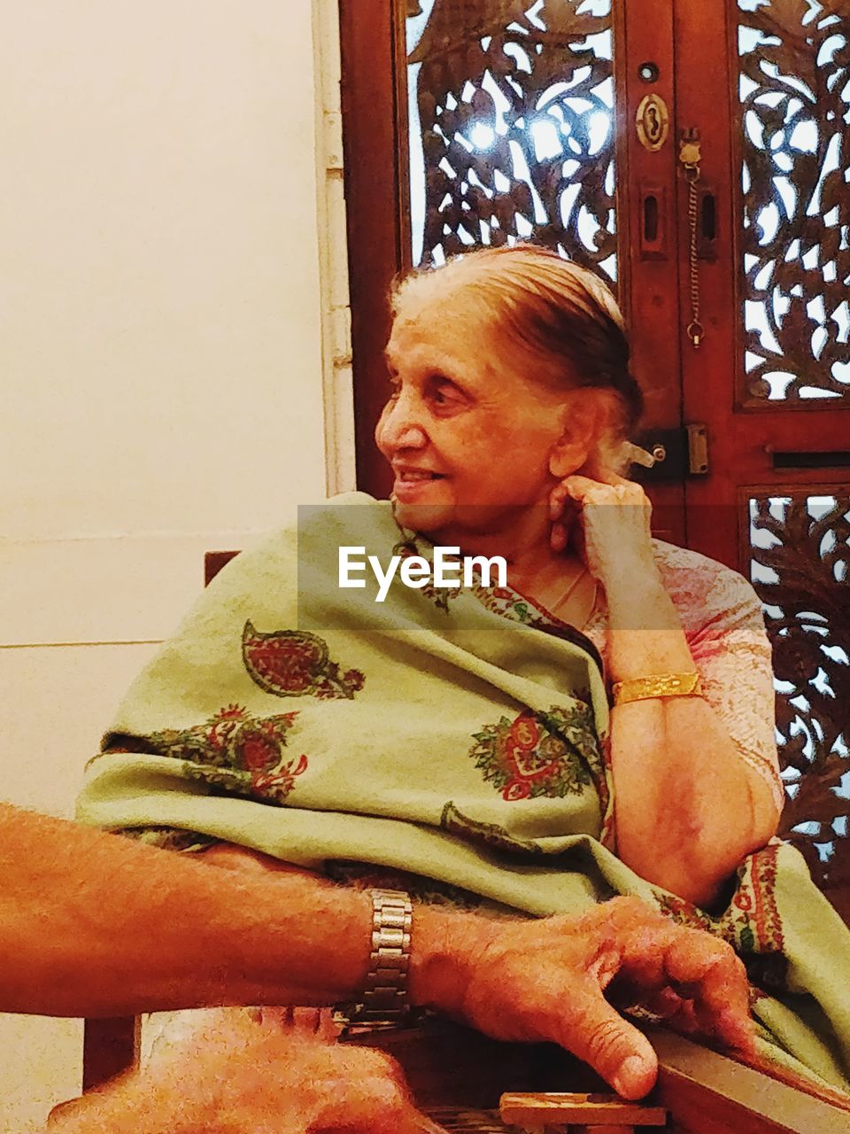 Senior woman looking away while sitting on chair at home