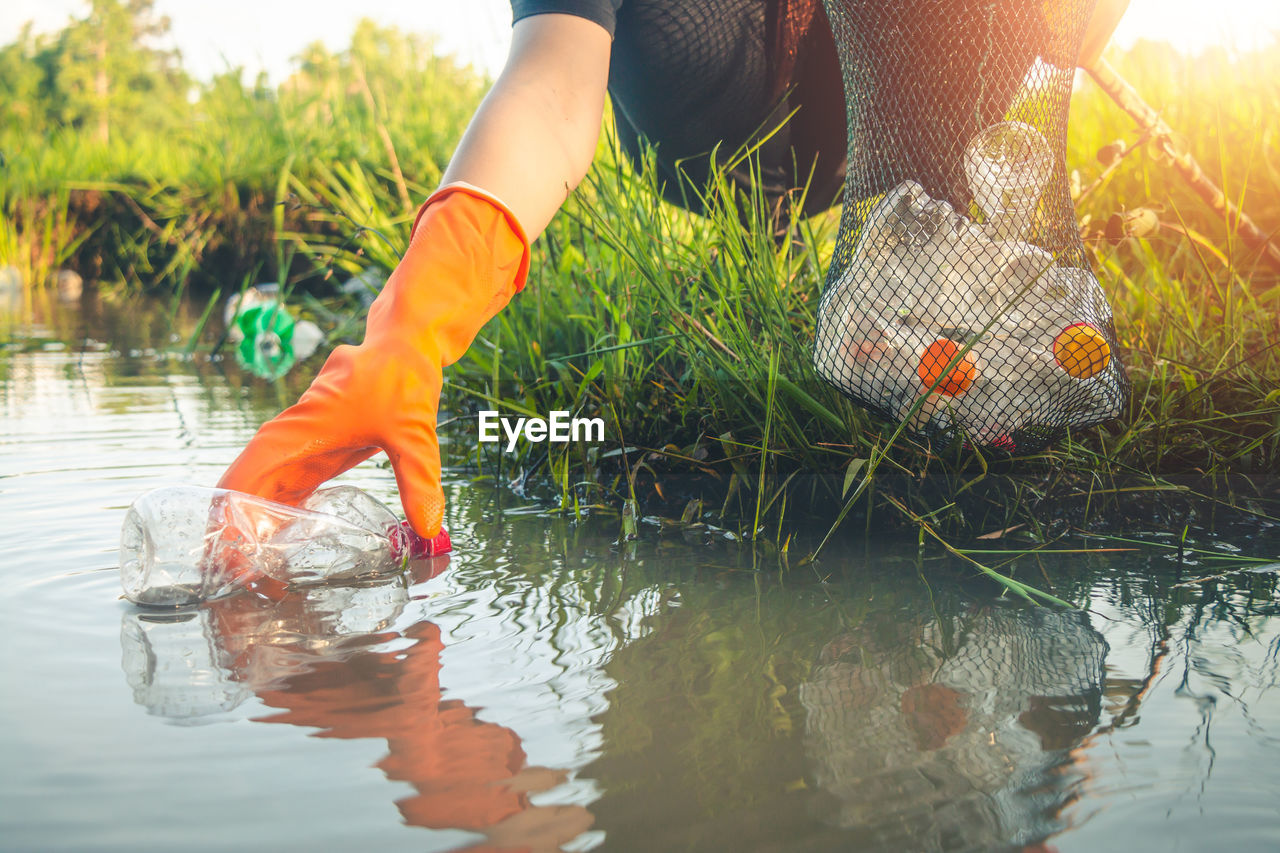 Low section of woman cleaning lake