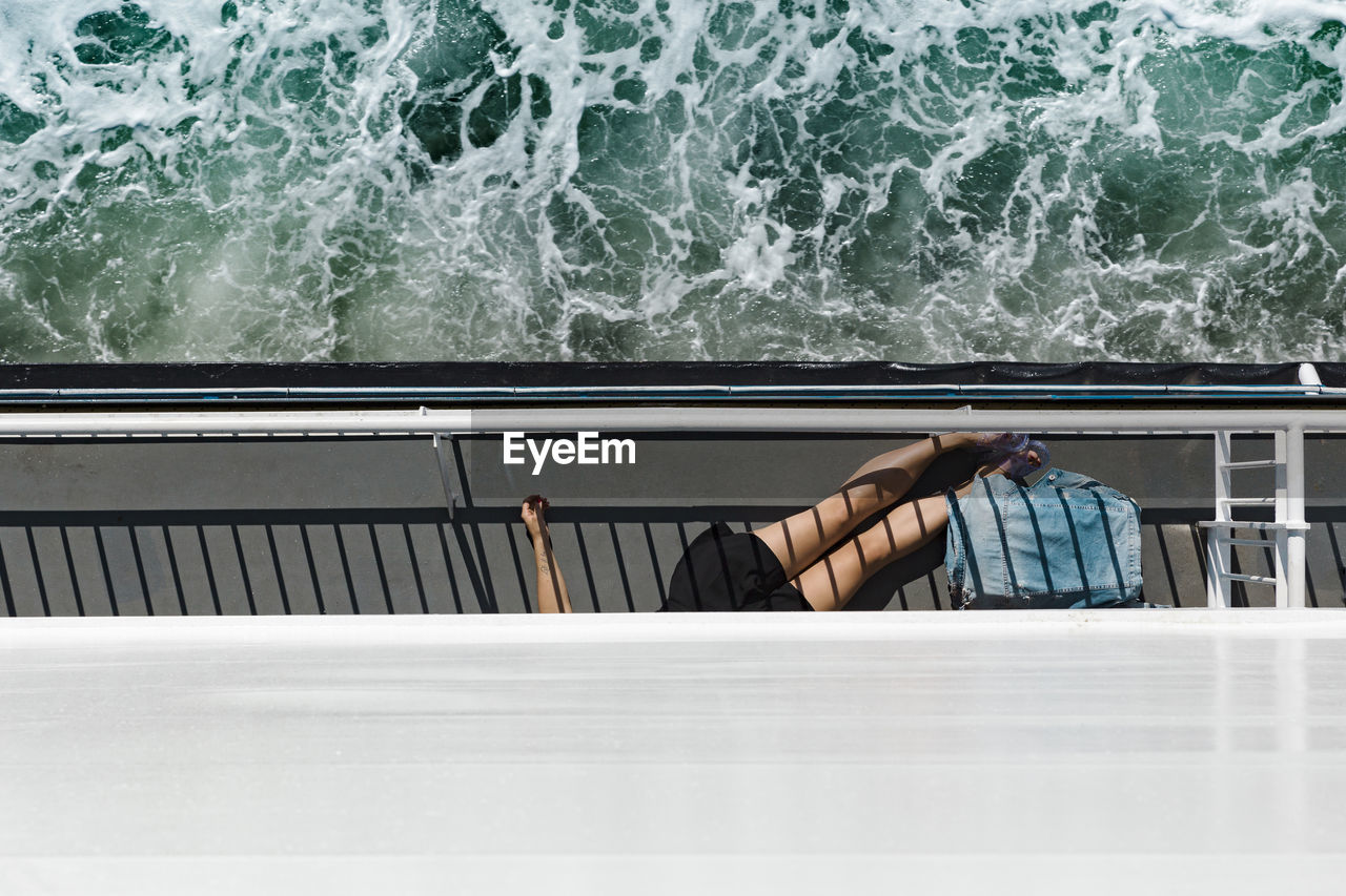 Low section of woman lying on boat at sea