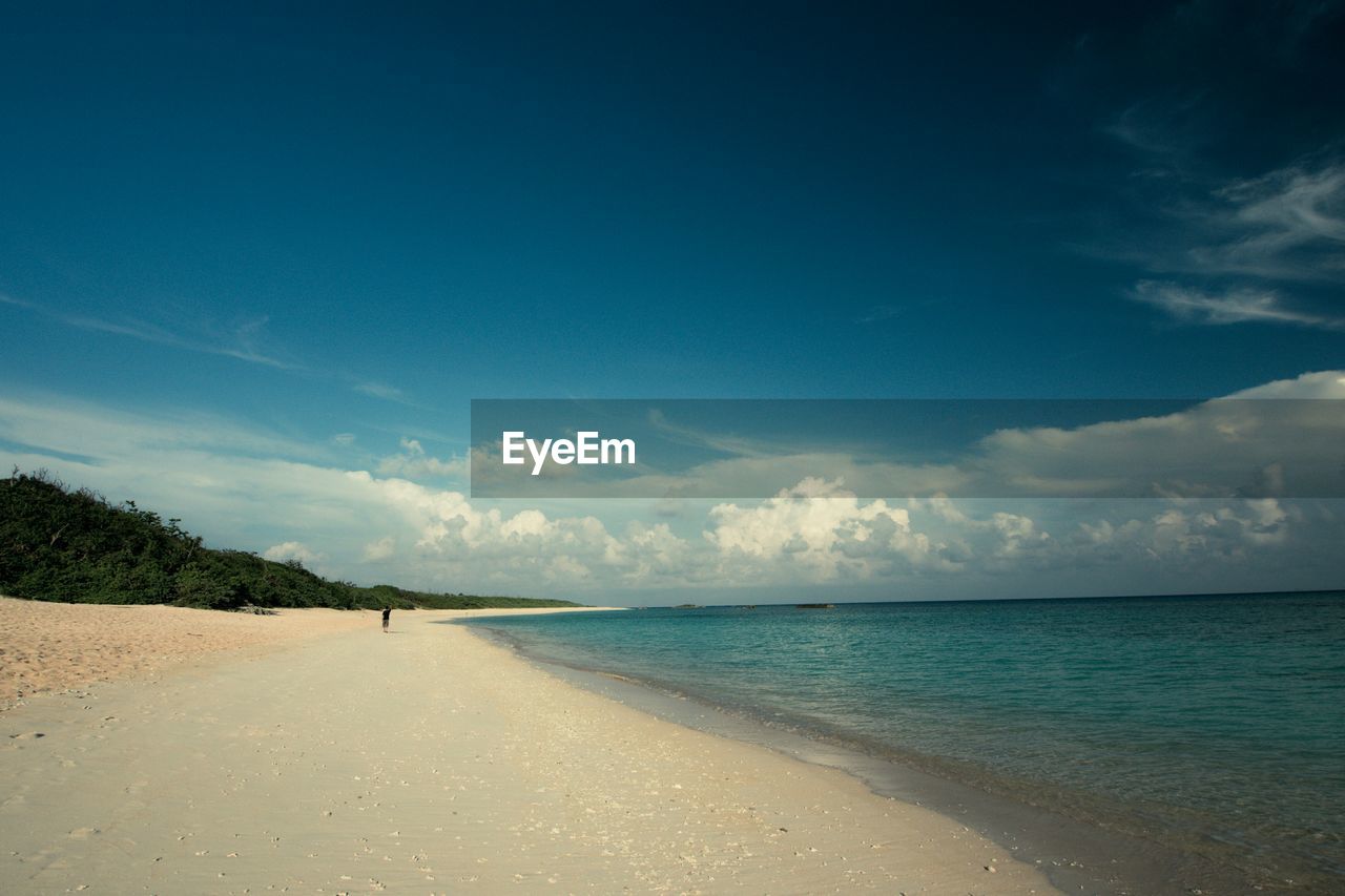 Scenic view of beach against cloudy blue sky