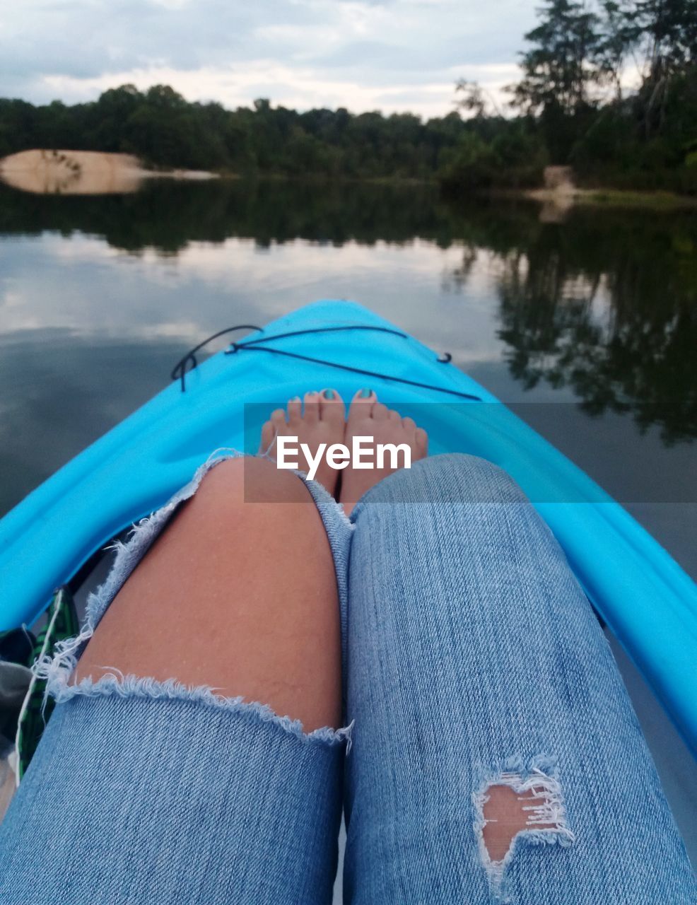Low section of woman relaxing on kayak in lake