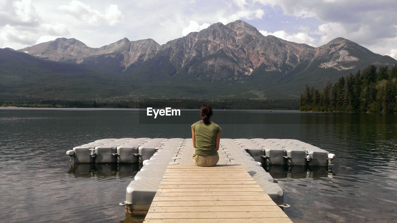 REAR VIEW OF MAN ON LAKE AGAINST MOUNTAINS